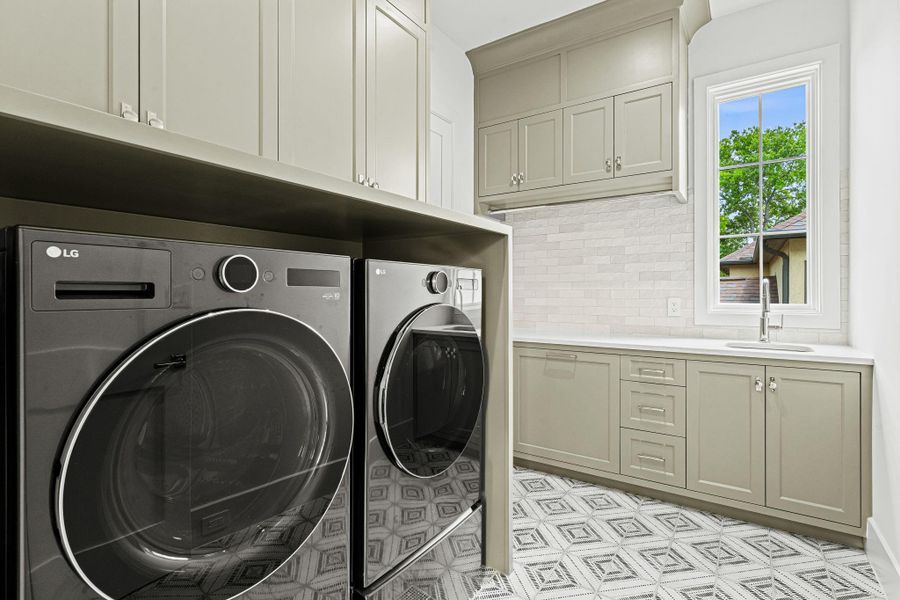 Conveniently located upstairs near all bedrooms, the utility room offers dual access from the hallway & primary closet for added ease. Quartz countertop paired w/ a Zellige tile backsplash & stainless steel sink, while ample storage, a built-in hamper & hanging bar enhance functionality. A patterned porcelain tile floor & window above the sink complete the space. Conveniently located upstairs near all bedrooms, the utility room offers dual access from the hallway & primary closet for added ease. Quartz countertop paired w/ a Zellige tile backsplash & stainless steel sink, while ample storage, a built-in hamper & hanging bar enhance functionality. A patterned porcelain tile floor & window above the sink complete the space.