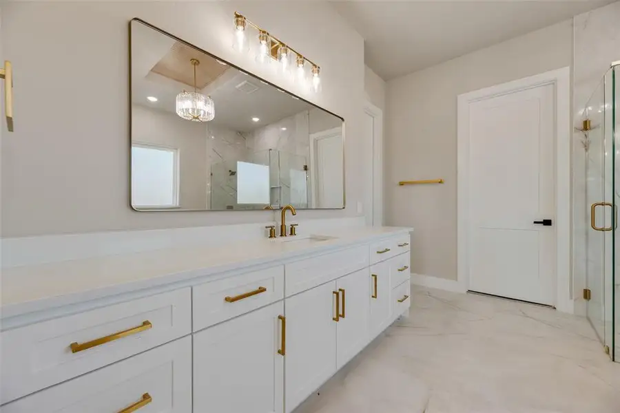 Bathroom featuring vanity, a marble finish shower, light marble finish flooring, and a chandelier