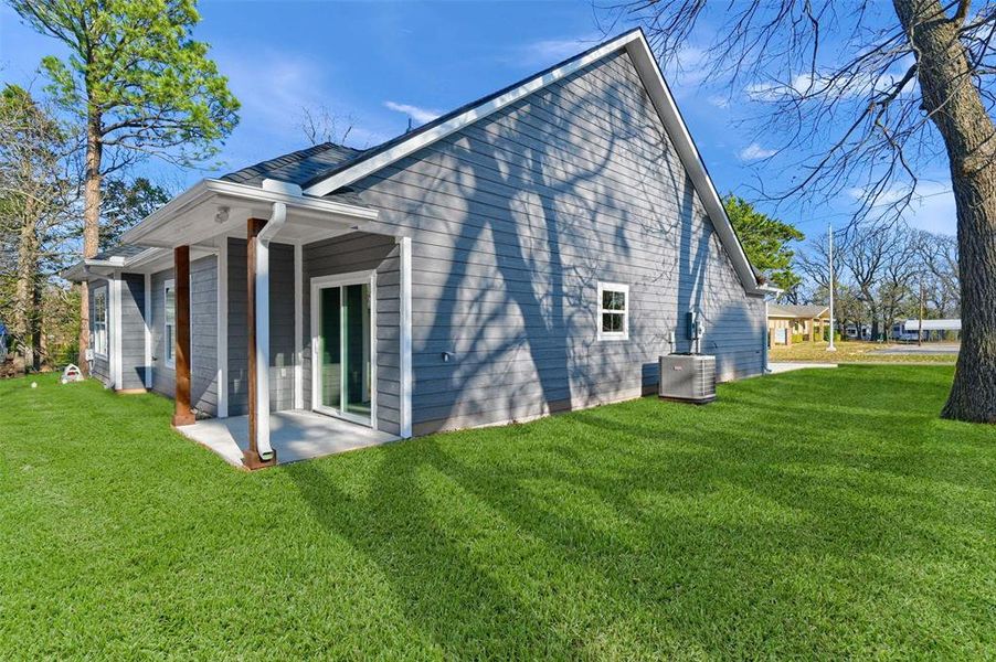 View of property exterior with central AC unit, a yard, and a patio