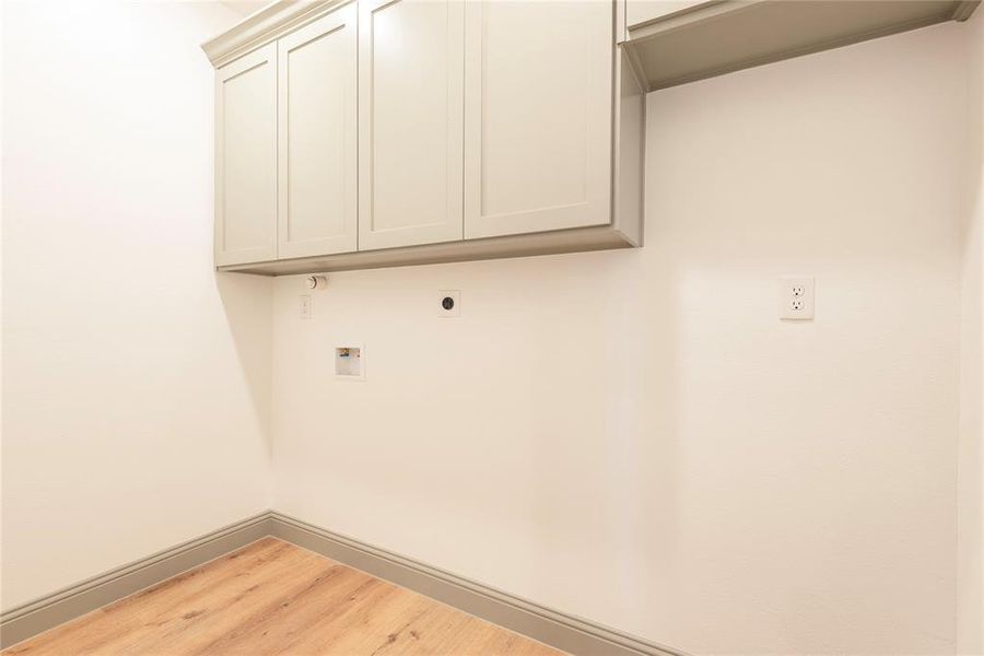 Laundry room featuring light wood-style flooring, hookup for a washing machine, cabinet space, and hookup for an electric dryer
