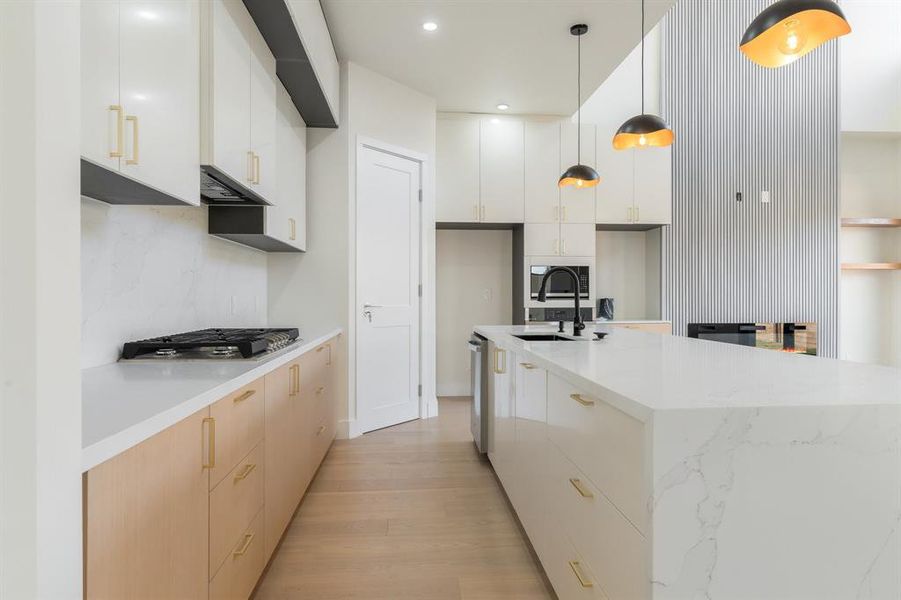 Kitchen featuring white cabinetry, hanging light fixtures, light stone countertops, modern cabinets, and a kitchen island with sink Kitchen featuring white cabinetry, hanging light fixtures, light stone countertops, modern cabinets, and a kitchen island with sink