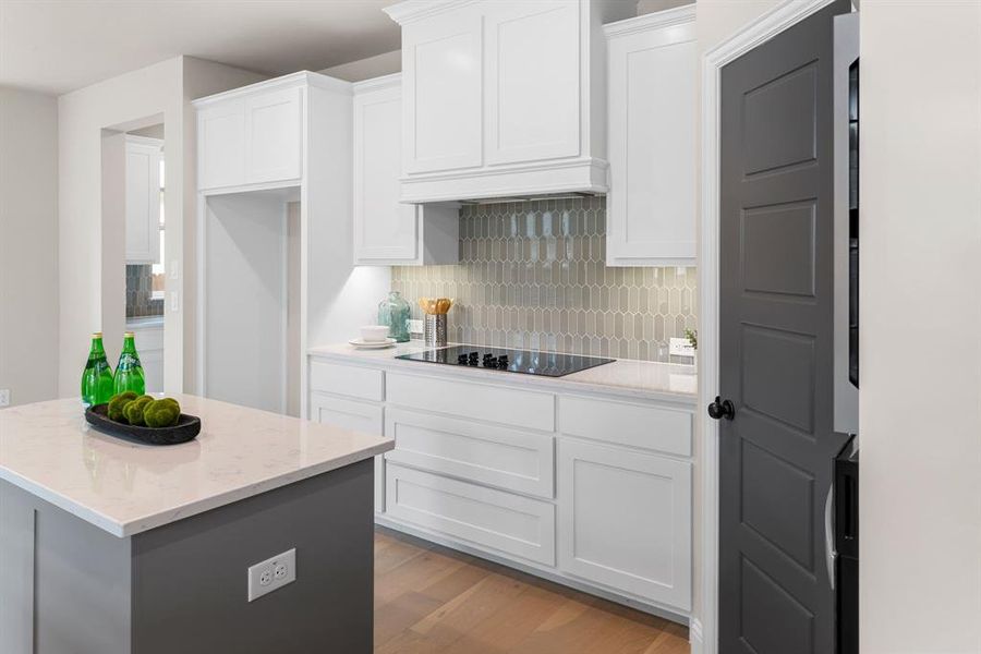 Kitchen featuring black electric cooktop, white cabinets, light stone counters, light hardwood / wood-style floors, and decorative backsplash