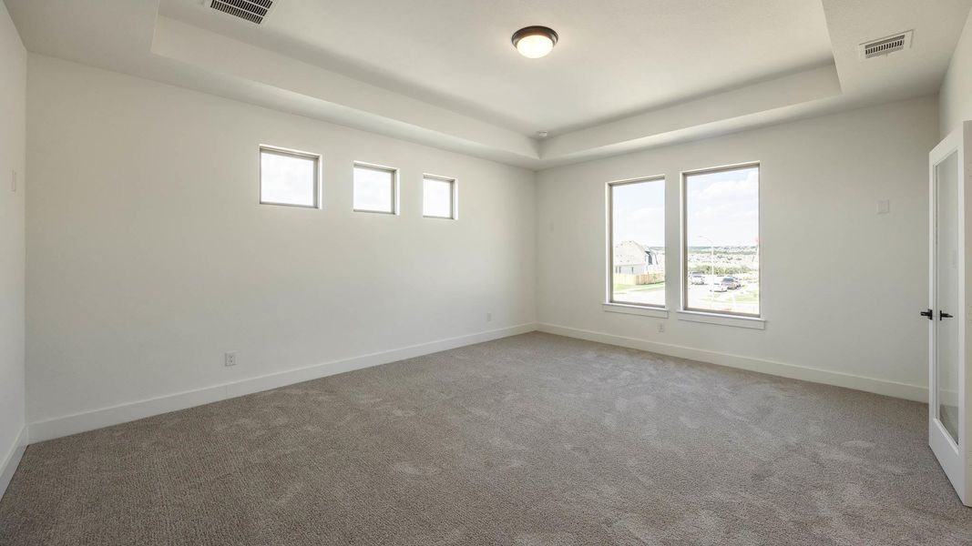 Spare room with a raised ceiling and light colored carpet