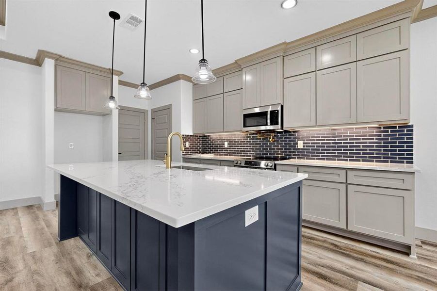 Kitchen with gray cabinets, decorative backsplash, light stone countertops, ornamental molding, and recessed lighting