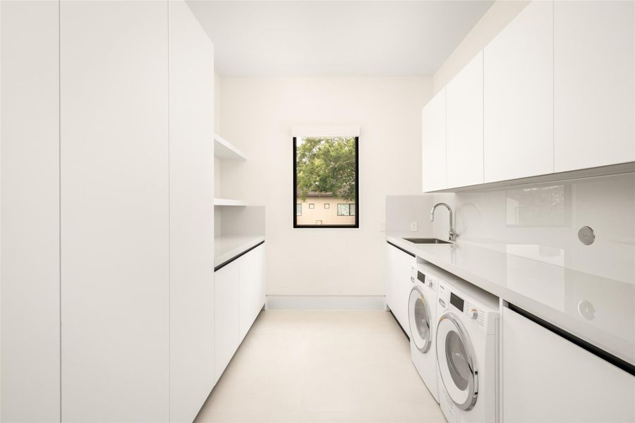 Dedicated upstairs laundry room with ample storage and utility sink.
