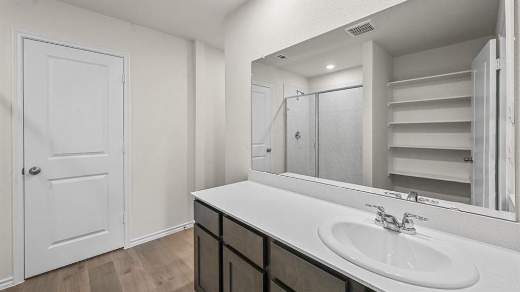 Full bath with a stall shower, dark wood-style flooring, and vanity