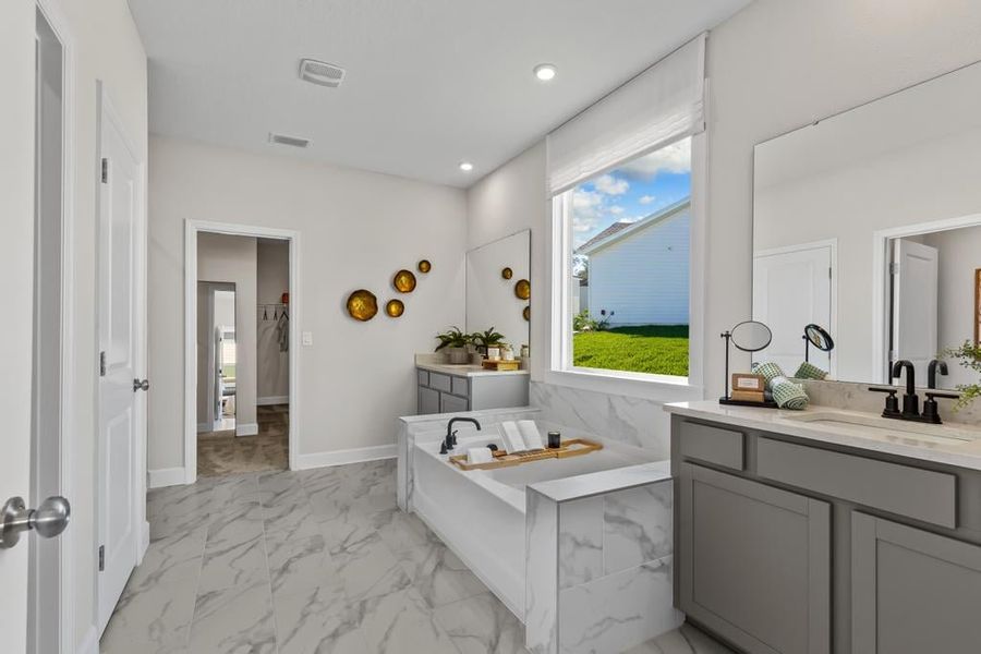 A bathroom with a tub sink and a large window.