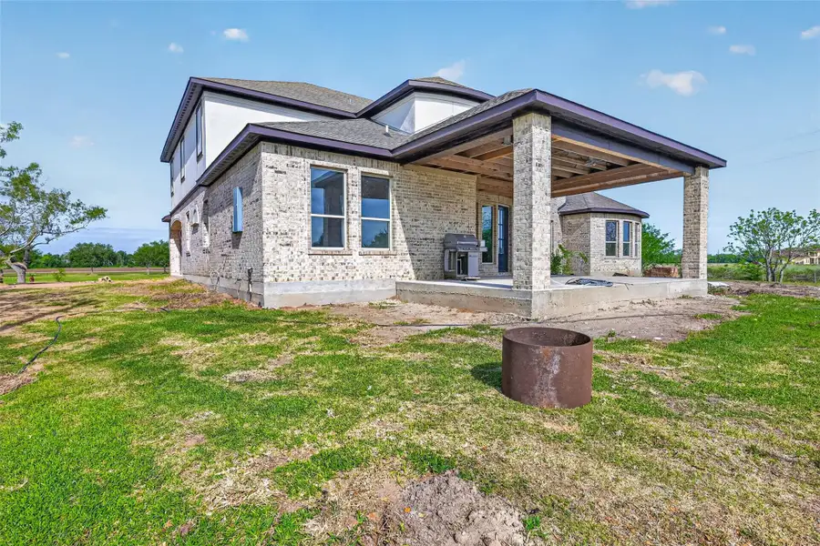 Rear exterior of Property 1 unfinished residence with covered patio, open backyard, and view of the existing lawn.