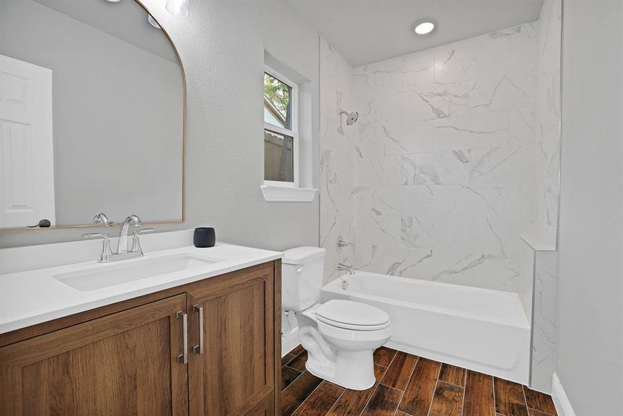 Full bathroom featuring toilet, tiled shower / bath combo, vanity, and wood-type flooring