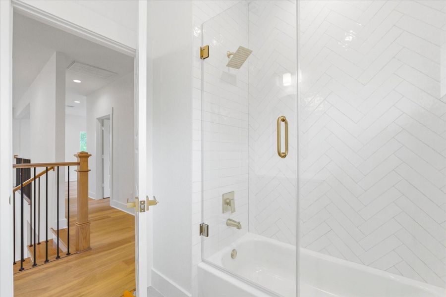 Another full bathroom upstairs features a practical shower/tub combo with a glass enclosure, offering both everyday convenience and a clean, polished look.