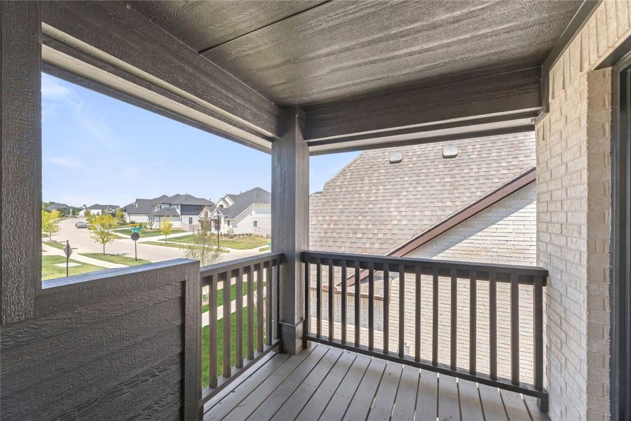 Covered second-floor balcony with wood deck, dark railings, and neighborhood street view Covered second-floor balcony with wood deck, dark railings, and neighborhood street view
