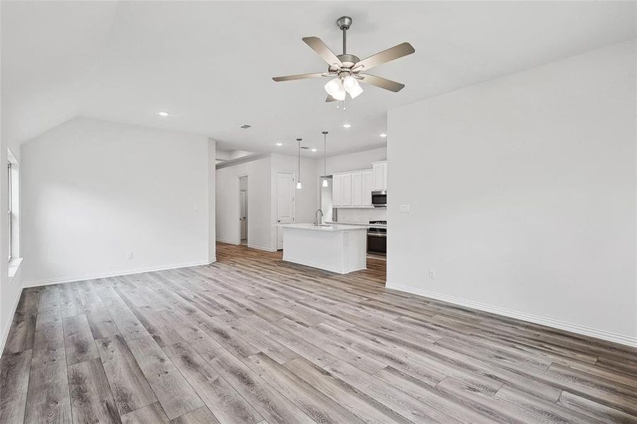 Unfurnished living room with light hardwood / wood-style floors, sink, lofted ceiling, and ceiling fan