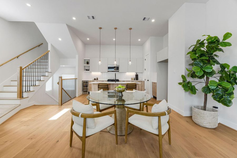 Bright and airy dining space overlooking the chef-inspired kitchen with high ceilings, contemporary finishes, wide-plank hardwood floors, and abundant natural light.