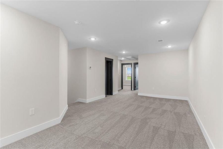 Spacious room featuring neutral carpeting, white walls, and recessed lighting