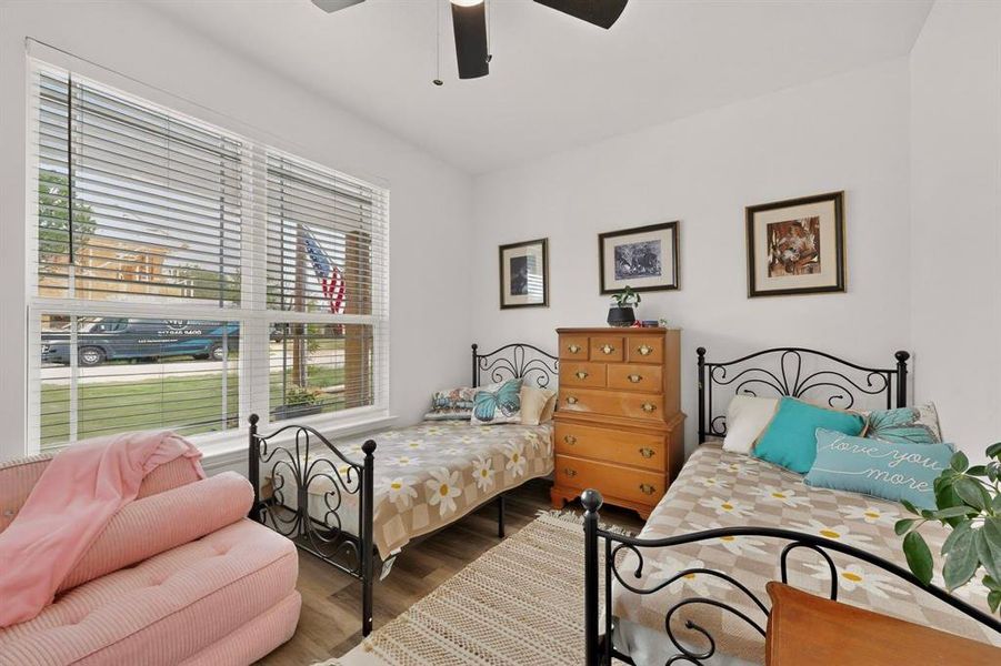 Bright room featuring a large window with horizontal blinds, wood-finish flooring, and a ceiling fan with integrated lighting