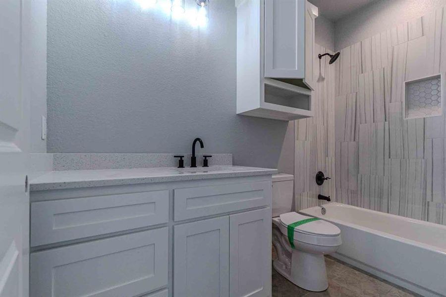 Bathroom featuring a textured wall, shower combination, and vanity Bathroom featuring a textured wall, shower combination, and vanity