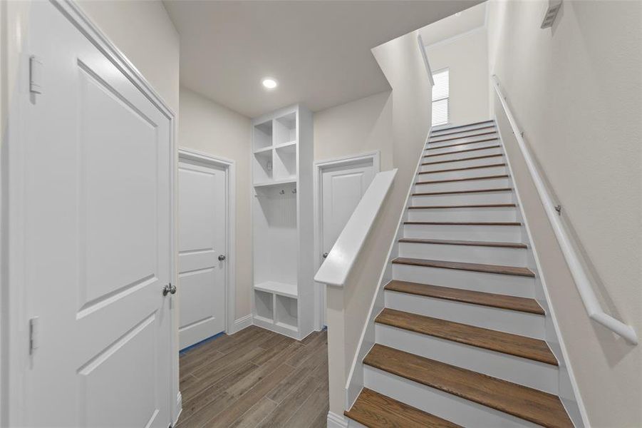 Staircase with wood finished floors and recessed lighting