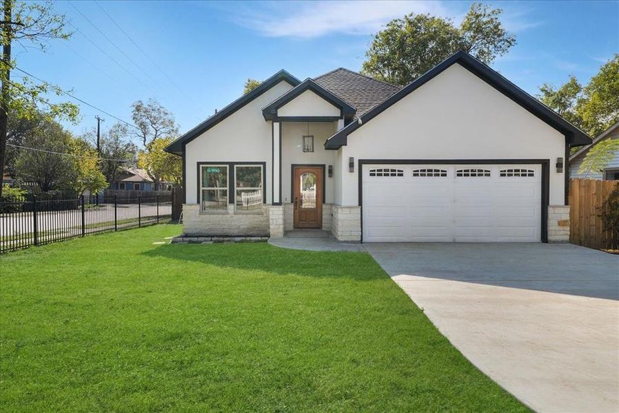 View of front of home with stone siding, stucco siding, driveway, and a garage