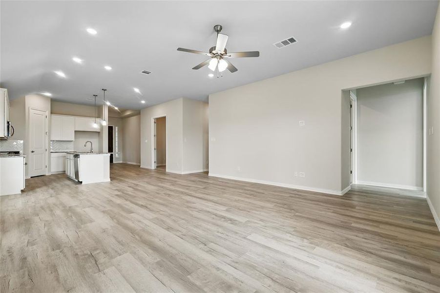 Unfurnished living room with ceiling fan, light wood-style flooring, a sink, recessed lighting, and baseboards