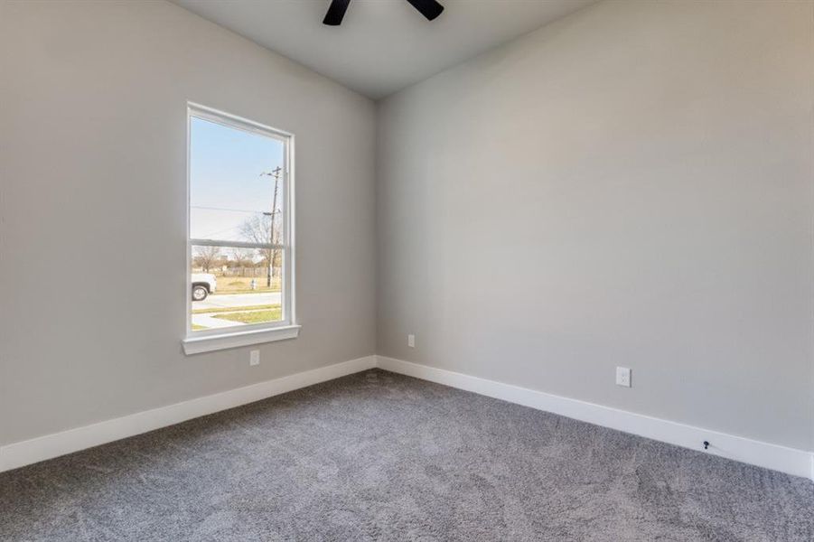 Carpeted spare room with baseboards and ceiling fan