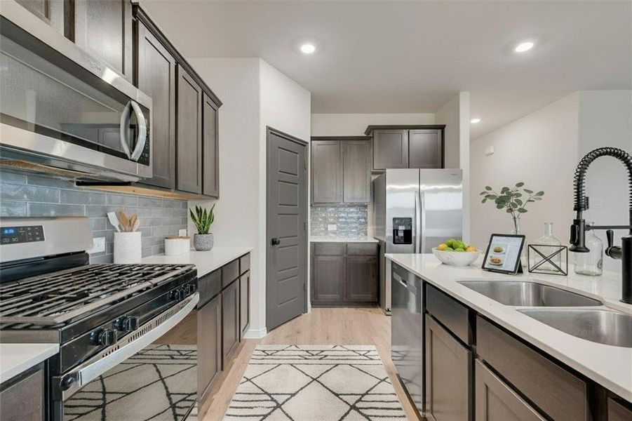Kitchen featuring stainless steel appliances, light wood-type flooring, light stone countertops, tasteful backsplash, and recessed lighting
