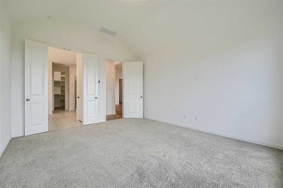 Unfurnished bedroom with lofted ceiling, light carpet, and a spacious closet