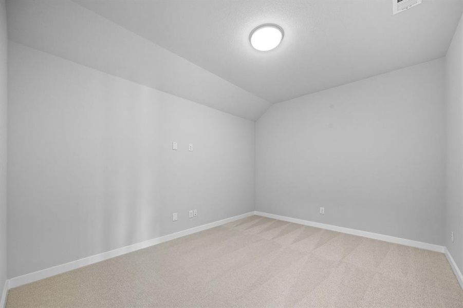 Unfurnished room with light colored carpet and vaulted ceiling