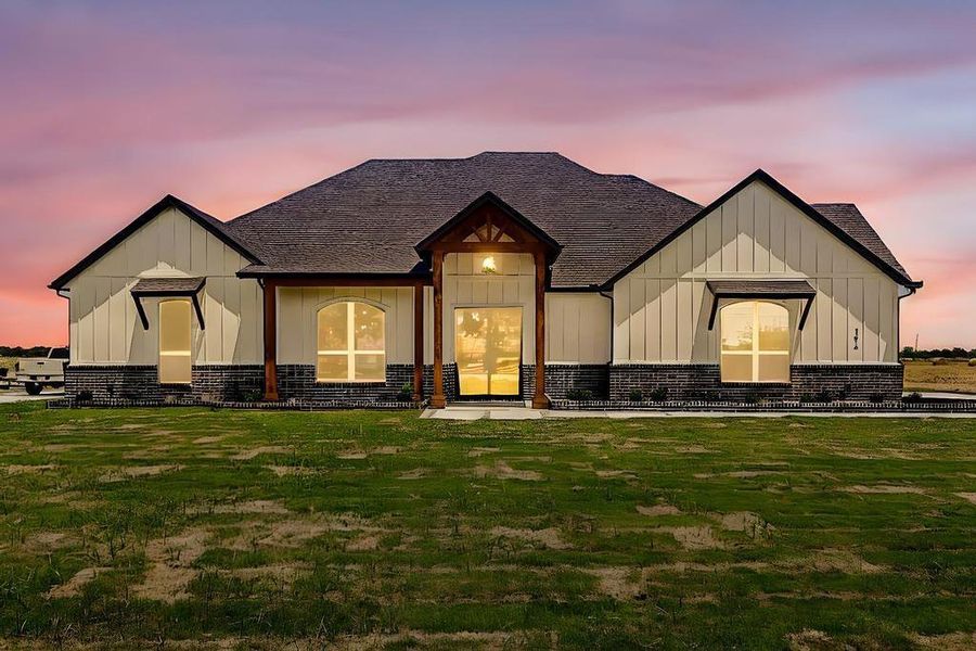 Modern inspired farmhouse featuring board and batten siding, a yard, and a shingled roof