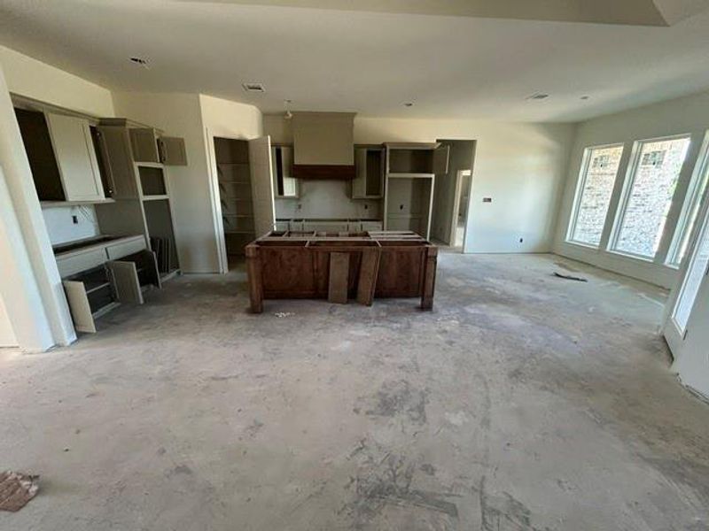 Open-concept interior featuring a central wood-finish island, white cabinetry, and recessed lighting