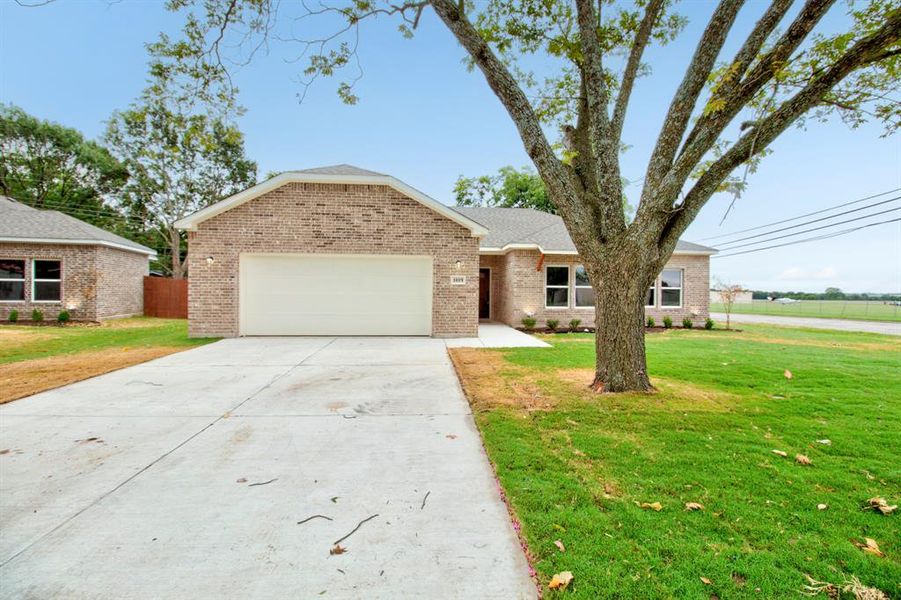 View of front of property featuring concrete driveway, brick siding, a front yard, and an attached garage
