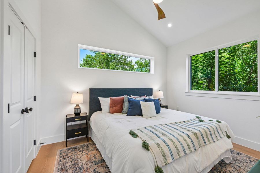 A tranquil primary bedroom with vaulted ceilings and verdant outdoor views among the trees. A tranquil primary bedroom with vaulted ceilings and verdant outdoor views among the trees.