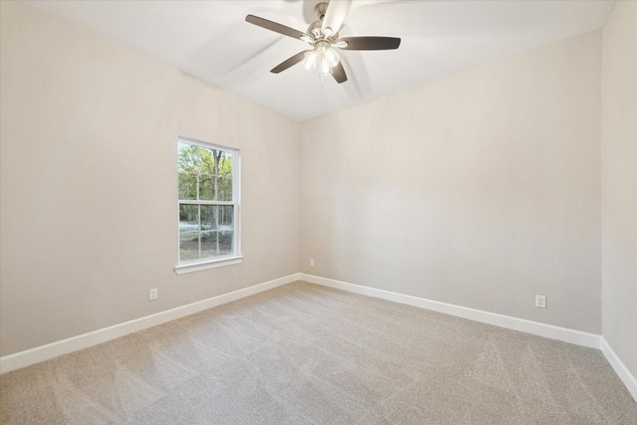 Third bedroom with carpeted flooring and lighted fan.  Single window looks to the front of the home.