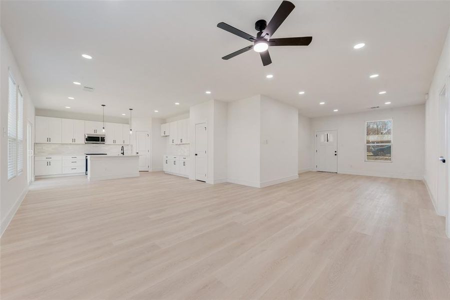 Unfurnished living room with ceiling fan and light hardwood / wood-style floors