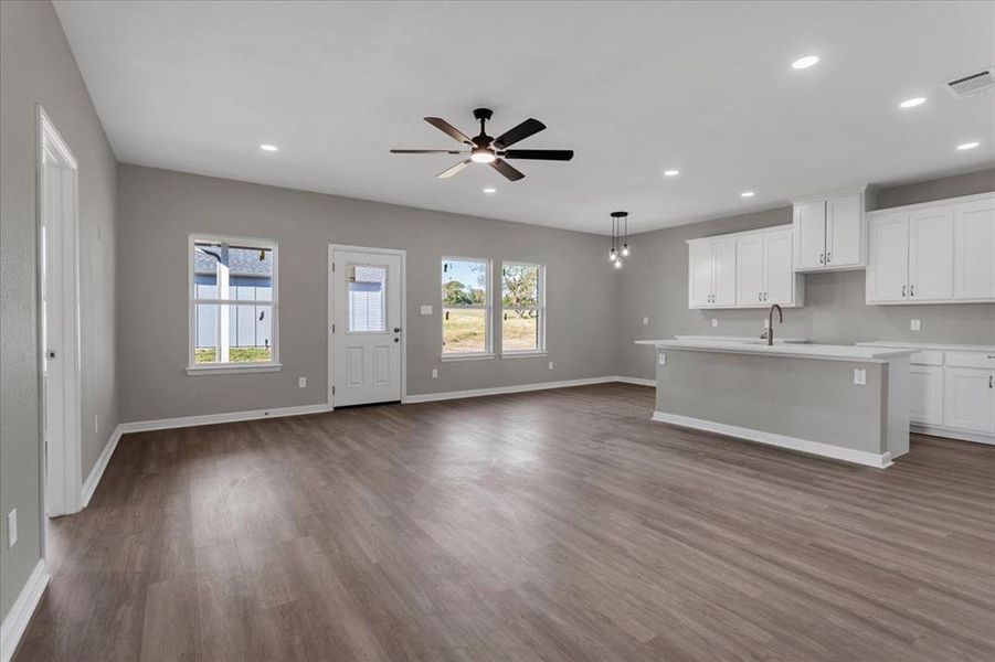 Kitchen with white cabinets, a kitchen island with sink, recessed lighting, dark wood finished floors, and a ceiling fan
