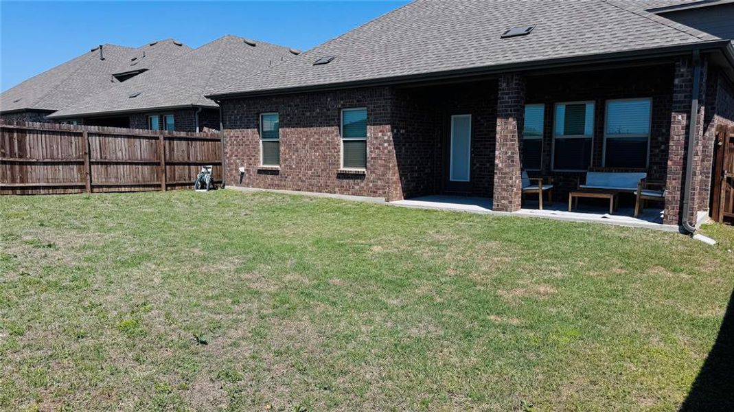 Rear view of house with brick siding, fence, and a lawn
