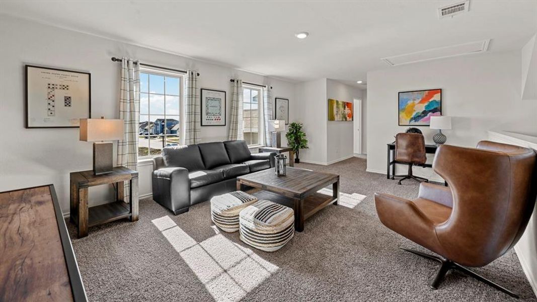 Spacious living area featuring carpet flooring, natural light from multiple windows, and a dedicated desk area Spacious living area featuring carpet flooring, natural light from multiple windows, and a dedicated desk area