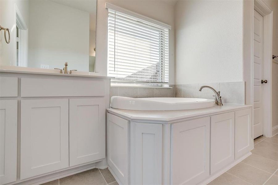 Bathroom with a washtub, vanity, and tile patterned floors