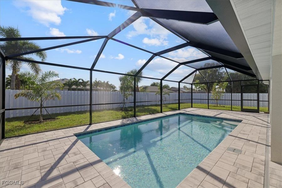 View of swimming pool with glass enclosure, a fenced backyard, and a patio