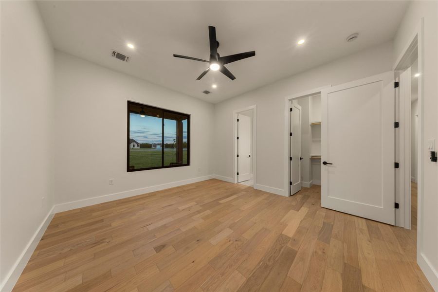 Unfurnished bedroom featuring a walk in closet, light wood-style floors, a ceiling fan, and recessed lighting