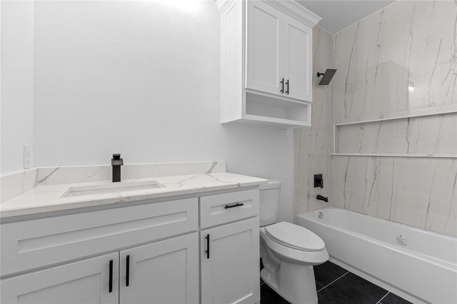 Full bathroom with vanity, toilet, tile patterned floors, and tiled shower / bath