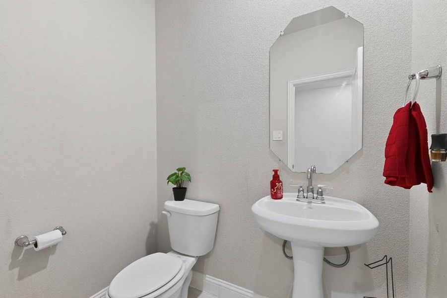 Half bath featuring toilet and a textured wall Half bath featuring toilet and a textured wall