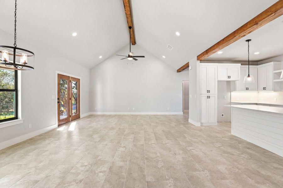 Vaulted ceilings and wood beams create an airy, modern living space with an open-concept kitchen. Vaulted ceilings and wood beams create an airy, modern living space with an open-concept kitchen.