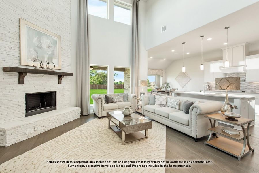 Open living room with two-story stone fireplace, neutral sofas, and hardwood floors open to kitchen Open living room with two-story stone fireplace, neutral sofas, and hardwood floors open to kitchen