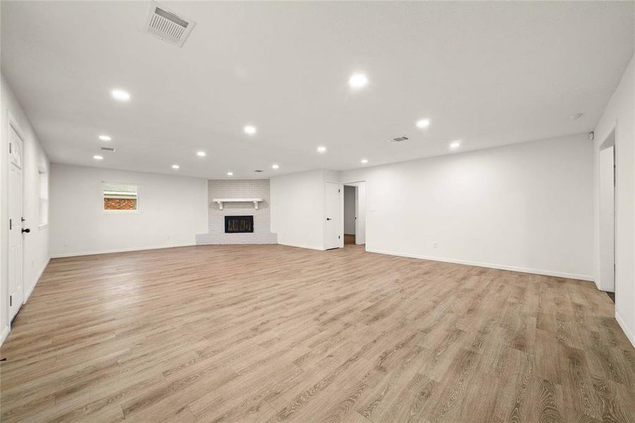 Unfurnished living room featuring light wood-style floors, a fireplace, visible vents, and recessed lighting Unfurnished living room featuring light wood-style floors, a fireplace, visible vents, and recessed lighting