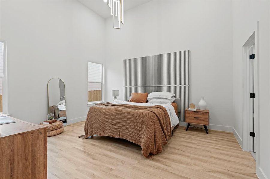 Bedroom with light wood-style flooring, a high ceiling, and baseboards Bedroom with light wood-style flooring, a high ceiling, and baseboards