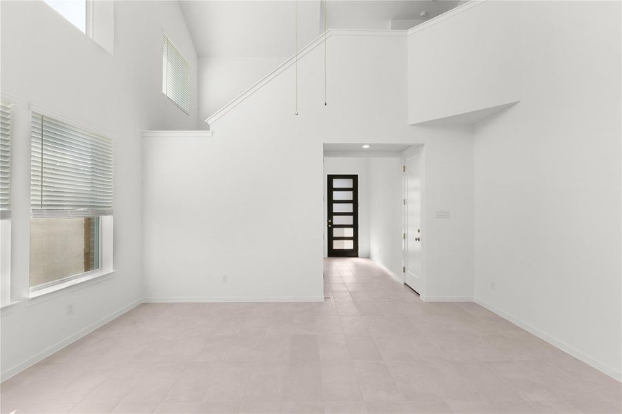 Empty room featuring a high ceiling, plenty of natural light, and baseboards
