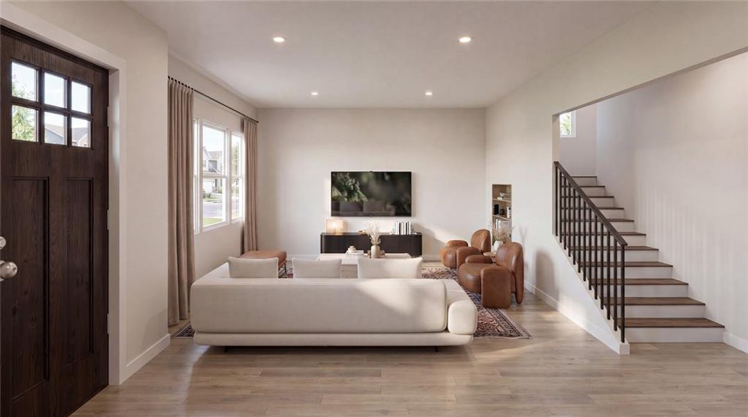 Open-concept living area featuring wood-finish flooring, recessed lighting, and a prominent staircase with dark railings