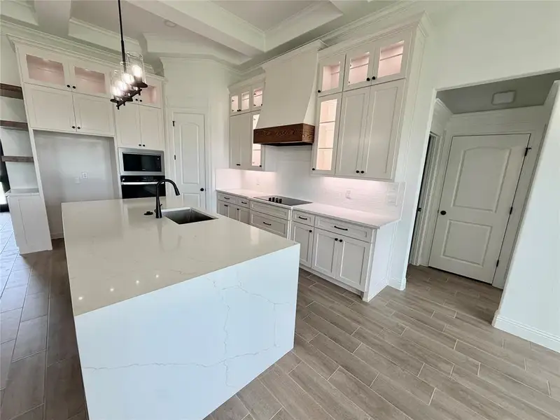 Modern kitchen featuring a large waterfall island with an undermount sink, quartz countertops, and a subway tile backsplash