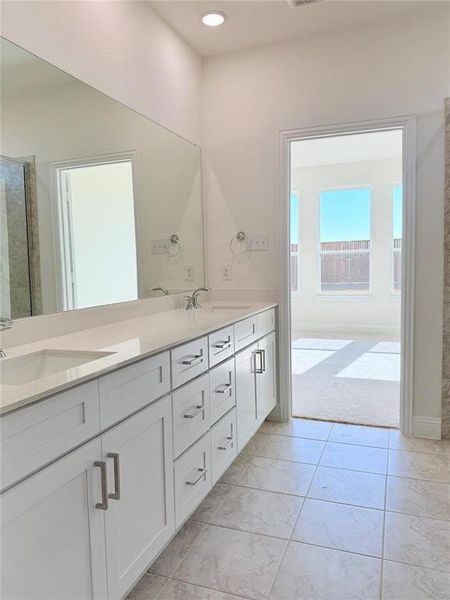 Full bath with double vanity, a shower with shower door, a sink, and tile patterned floors