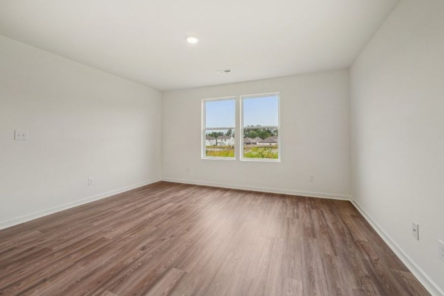 A room with a wood floor and a window with a tree outside. A room with a wood floor and a window with a tree outside.